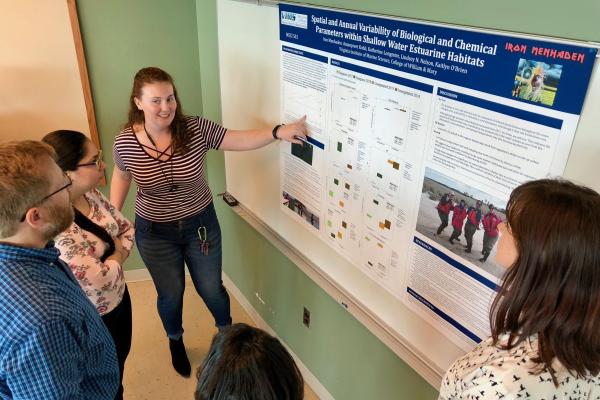 A Batten School &amp; VIMS student gives a research poster presentation to a group of onlookers.