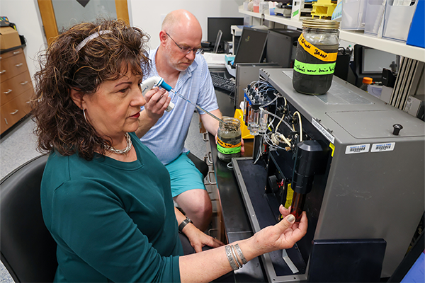Batten School &amp; VIMS scientists Mary Ann Vogelbein (front) and Hamish Small (back) conduct “forever chemical” research using a biosensor tool. Photo by John Wallace.
