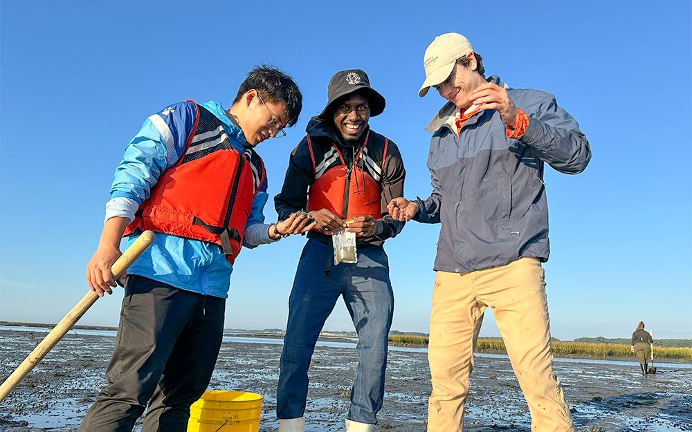 New Batten School & VIMS graduate students Peichen Huang (left), Abdoulie Jallow (center) and Ari Siegel (right) gathering samples on a mudflat. Photo by Ethan Smith.