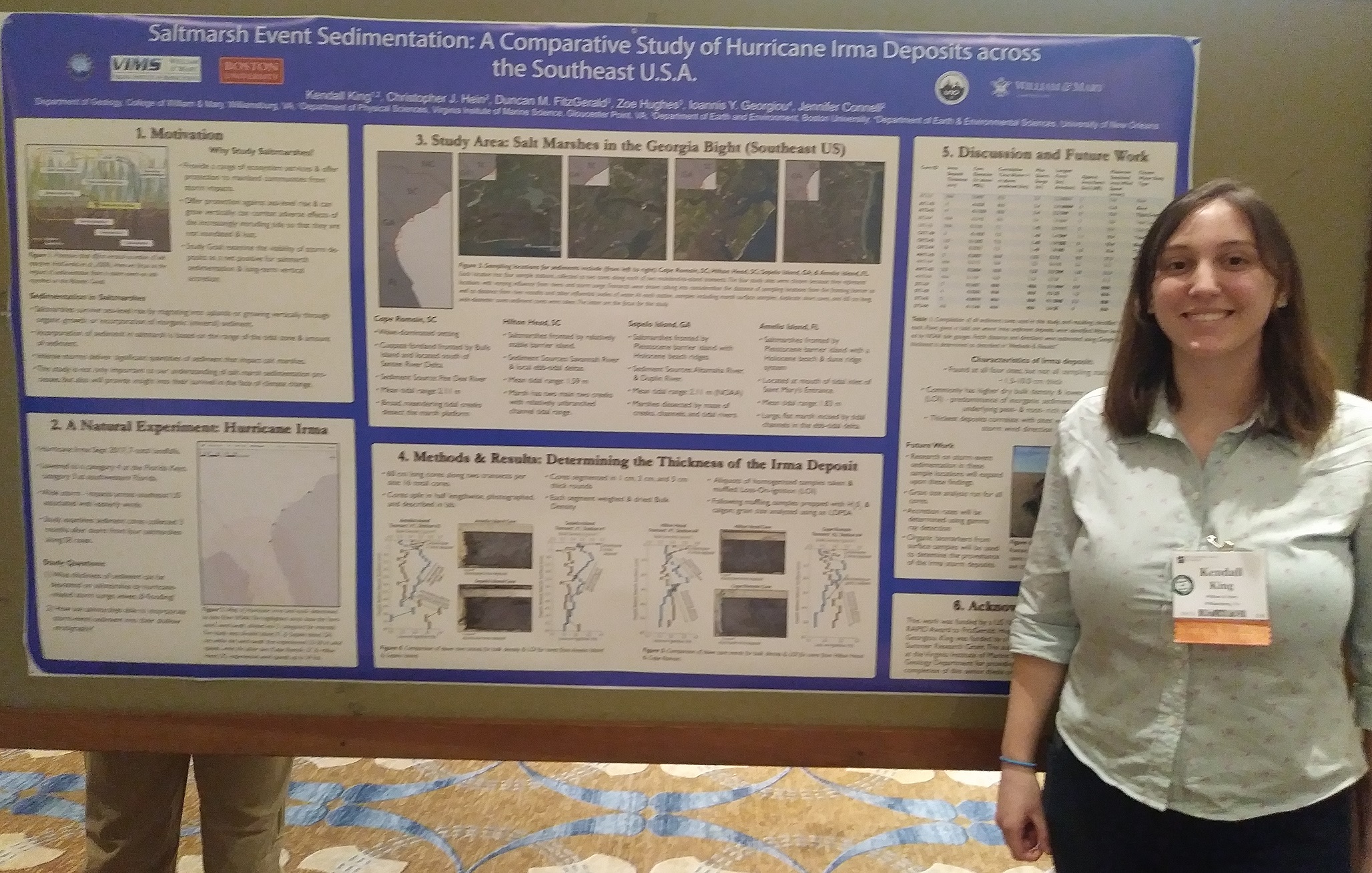 Kendall King smiles in front of research presentation poster at conference