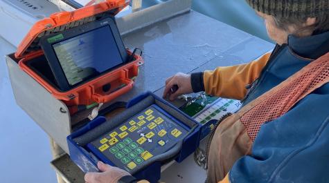 A scientist uses an electronic measuring board connected to a data tablet to record fish and crab lengths.