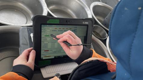 A scientist records environmental and station data on a digital tablet